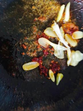 锅中入油，下郫县豆瓣酱翻炒片刻，放葱蒜。