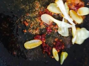 锅中入油，下郫县豆瓣酱翻炒片刻，放葱蒜。