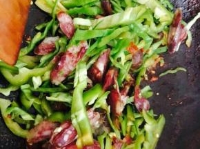 倒入腊肠和尖椒，翻炒片刻。