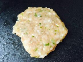 将调好的肉馅放到电饼铛里，用铲子压平，整形。