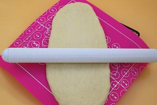 发好后的面团取出排气，尽可能擀成长方形（取出的动作不是用手直接去把面团扯出来而是用软刮板或者手指从面团的底部往上捞出来）