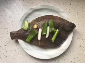 鱼身抹盐和料酒，覆盖葱姜。腌制20分钟