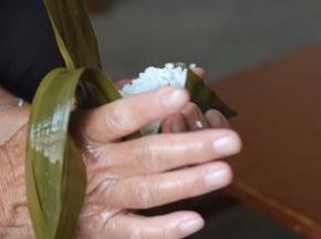 11.左手拿着粽子用你的右手向前推粽叶，盖上口