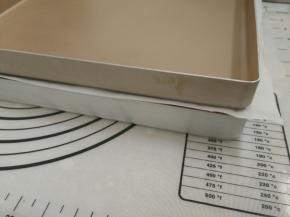 10.面团上盖油纸，油纸上再盖上一个平烤盘，进行二次发酵，烤箱内放一碗热水保持面团湿度