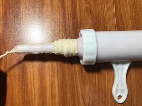 灌肠器罐好肉馅，灌肠嘴套入肠衣，肠衣尾端系扣子。