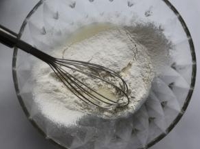 将低筋面粉过筛到搅拌好的牛奶油糊里，用手动打蛋器以Z字型方式搅拌到无干粉即可