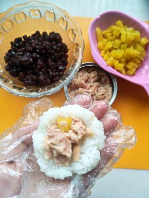 先做金枪鱼寿司戴上手套拿一团米饭，按扁中间放入金枪鱼盒寿司萝卜，用手捏紧呈自己喜欢的样子即可。我做了两种口味的寿司，便于区别金枪鱼寿司我捏成了三角。