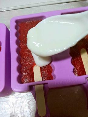 拿出冻好的草莓冰棍上面在倒满酸奶。继续放冰箱冷冻。