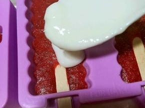 拿出冻好的草莓冰棍上面在倒满酸奶。继续放冰箱冷冻。
