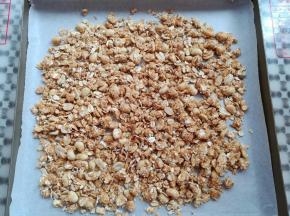 把混合后的麦片倒入铺了油纸的烤盘里，预热烤箱上火130度，下火160度