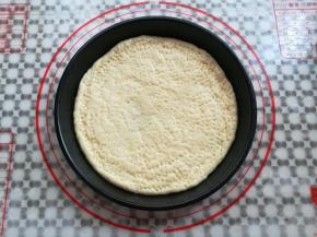 把面团放入抹了油的披萨盘中，在面团上用叉子戳出小洞