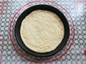 把面团放入抹了油的披萨盘中，在面团上用叉子戳出小洞