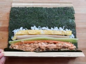 提起寿司帘的末端，紫菜包住饭团的材料