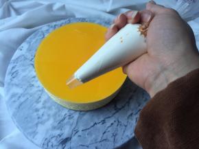 把打发好的淡奶油装进裱花袋内，在芝士蛋糕表面挤上简单的花式，切一点芒果放在奶油上，简单装饰即可