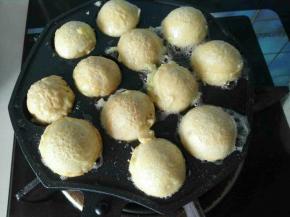 4、锅烧热，用刷子刷层油倒入一半面糊，中间放入包菜碎和章鱼粒，再倒入面糊，把锅倒满，全程中小火，两分钟后用竹签或铁签顺球形边一推，章鱼小丸子就翻面了，一直在锅子滚，直到颜色满意为止。