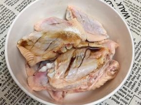 鸡翅洗净，在背面画两刀放入碗中，调入盐和鸡精，倒入酱油。