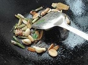 6. 将腌制鱼的葱姜蒜捞出，放入倒有底油的锅中炝锅