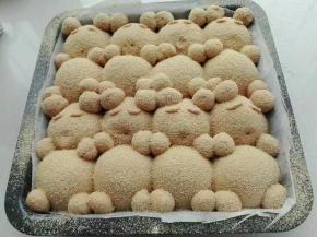 9. 发酵好的面团分别将做好的耳朵，手，脚，眉毛沾点水摆在相应位置上，且表面筛一层黄豆粉