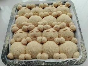 9. 发酵好的面团分别将做好的耳朵，手，脚，眉毛沾点水摆在相应位置上，且表面筛一层黄豆粉