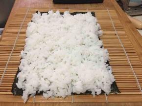 将米饭加入少许寿司醋搅拌，均匀铺在海苔上。注意不要太厚，我的太厚啦！