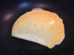 蛋液慢慢凝固后，掀起一边的蛋皮向另一边卷起，慢慢卷起直到全部卷完。