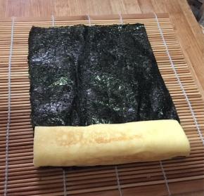 将厚蛋烧放在半片海苔上卷住，不服贴的部分可以沾点水。