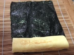 将厚蛋烧放在半片海苔上卷住，不服贴的部分可以沾点水。
