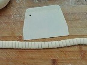 7. 将50克的面团搓成长条可以围住图五的长度，用刮板压出痕，如图所示