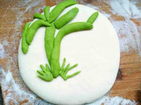 绿色面团取一小块搓长，摁扁做出树干，抹少许水沾到面饼合适的位置，然后用相同的办法搓出枝条的样子，固定在合适位置