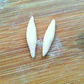 取两小块白色面团搓长一头略尖，做出兔子耳朵