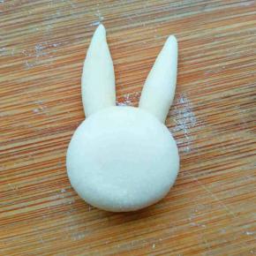 另取略大的一块揉圆并稍微摁扁，沾到耳朵下边