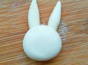 另取略大的一块揉圆并稍微摁扁，沾到耳朵下边