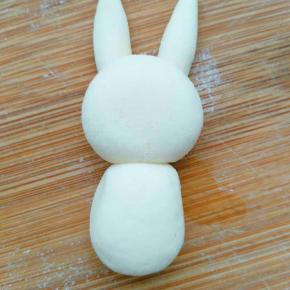 再取一块白色的捏成长方形稍摁下，但不要用力过大，摁的太扁，固定在头的下边做身体