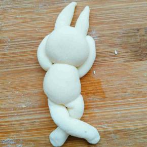 搓两个略粗的条做兔子腿，两腿交叉，翘起来，固定在身体下方，兔子完成。