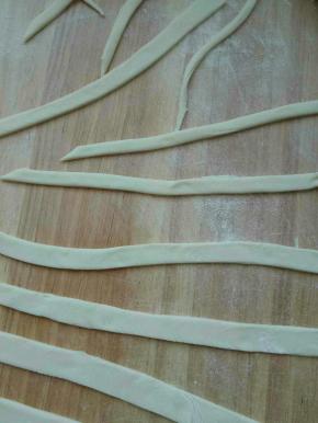 用手压住另一面，刀子将面割成一条一条的。