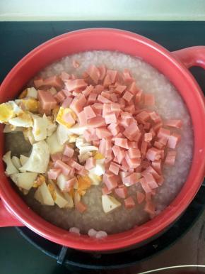 加入切丁的咸蛋和火腿，搅拌均匀，加少许盐和鸡精。关火利于砂锅的余温闷5分钟左右。