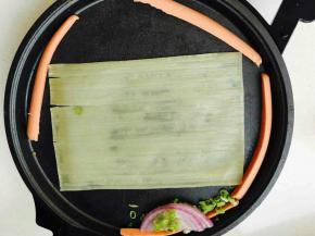 刷好油的饼铛上放冷面胚子，火腿肠，香葱及葱头。