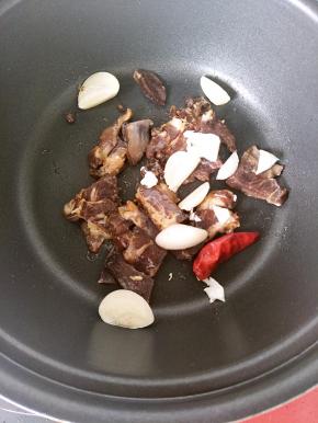 锅内少放一点油，倒入腊肠和蒜片炒香