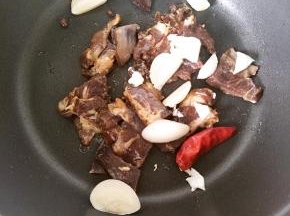 锅内少放一点油，倒入腊肠和蒜片炒香