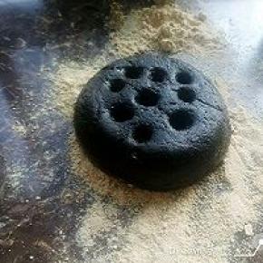 取一个两端开口的圆柱形器皿，容器内壁均匀地抹上油防粘，将容器放在盘子上，取适量的的黑芝麻糯米煮成的粘糕放入容器中
用沾了油的勺子背将其填平压实。填平压实后，筷子上粘少许油，在表面上扎几个孔。然后将容器向上提起，再盘子周围撒上黄豆粉当做煤灰。