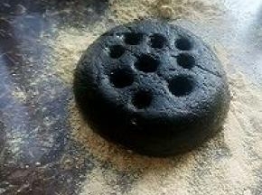 取一个两端开口的圆柱形器皿，容器内壁均匀地抹上油防粘，将容器放在盘子上，取适量的的黑芝麻糯米煮成的粘糕放入容器中
用沾了油的勺子背将其填平压实。填平压实后，筷子上粘少许油，在表面上扎几个孔。然后将容器向上提起，再盘子周围撒上黄豆粉当做煤灰。