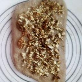 发酵好的面团分成两份，用手压扁放入切碎的核桃。有上而下卷起来。