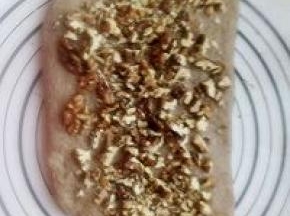 发酵好的面团分成两份，用手压扁放入切碎的核桃。有上而下卷起来。