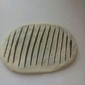 用手按扁，擀成椭圆形，用利刀在中间划开多条口子，间隔距离要相等。能看到豆沙但又不会割穿底下的面皮。