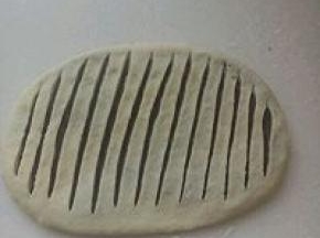 用手按扁，擀成椭圆形，用利刀在中间划开多条口子，间隔距离要相等。能看到豆沙但又不会割穿底下的面皮。
