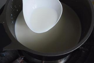 奶锅放灶头上，将锅中液体煮沸