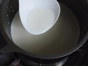 奶锅放灶头上，将锅中液体煮沸