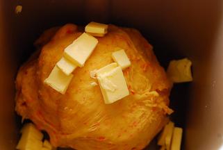 待面团能够拉出粗膜，放入软化的黄油，继续揉一个程序，约20分钟，至面团能拉出透明的手套膜状态