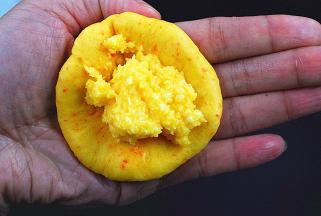 取小面团1只，擀成圆饼状，取一勺椰蓉馅放在饼状面团中（椰蓉馅分成9份）