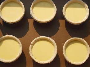蛋挞皮取出，放金盘中，倒入挞液